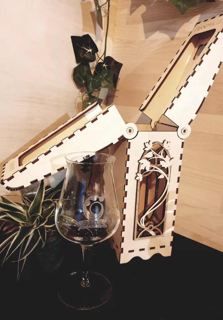 Réalisation d'un coffret pour bouteille au motif fleural. Ce coffret est ajouré et s'ouvre en deux par le haut.