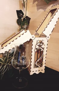 Réalisation d'un coffret pour bouteille au motif fleural. Ce coffret est ajouré et s'ouvre en deux par le haut.